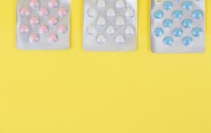 different colors of pills on a yellow surface