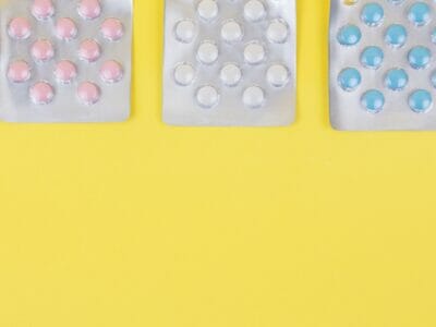 different colors of pills on a yellow surface