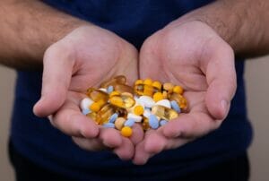 man holds different vitamins in hands